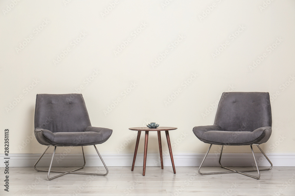 Room interior with modern chairs and table near light wall Stock Photo ...