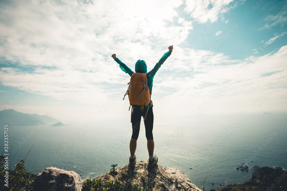 Successful hiker outstretched arms at seaside mountain top cliff edge - obrazy, fototapety, plakaty 