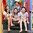 © nuiiko - Happy Asian kids sitting at playground together in the park outdoor.