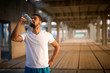 Young sporty athlete drinking water after hard training. Fitness and exercising. Body hydration.