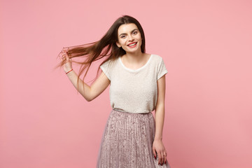 Beautiful cheerful young woman in casual light clothes posing isolated on pastel pink wall background, studio portrait. People sincere emotions lifestyle concept. Mock up copy space. Holding hair.