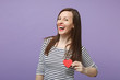 © ViDi Studio - Young brunette woman girl in casual striped clothes posing isolated on violet purple background studio portrait. People sincere emotions lifestyle concept Mock up copy space Hold two little red hearts