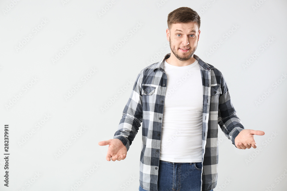Confused young man on light background