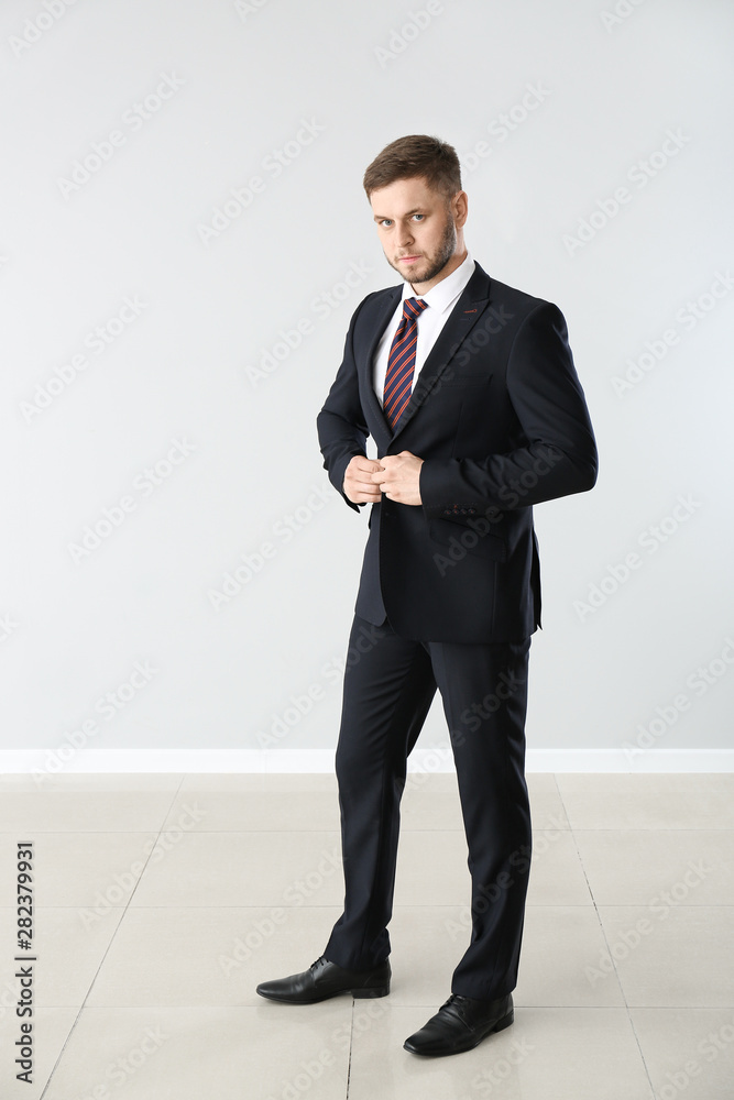 Handsome businessman near light wall
