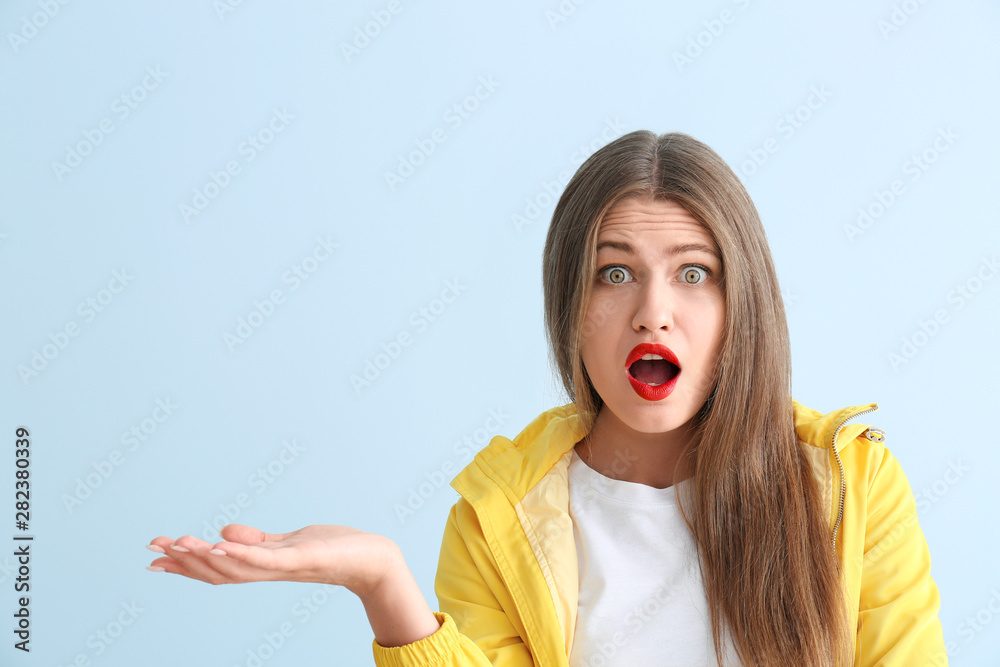 Surprised young woman on color background
