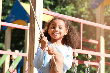 Wall Mural - Cute African-American girl having fun on playground outdoors