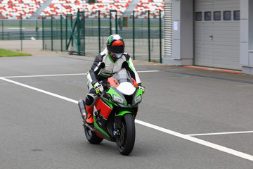 Wall Mural - Motorcyclist on a racing motorcycle back to the pits