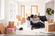 Couple Taking A Break And Sitting On Sofa Celebrating Moving Into New Home With Champagne