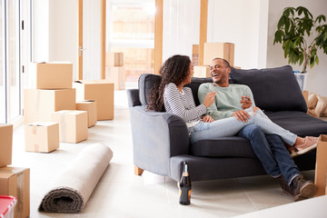 Wall Mural - Couple Taking A Break And Sitting On Sofa Celebrating Moving Into New Home With Champagne