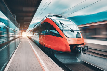 Wall Mural - high speed orange train in motion on the railway station at sunset. modern intercity passenger train