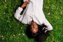 Portrait Of Beautiful African American Woman Laying On Green Grass In Park