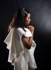 Portrait of a beautiful young African woman in white dress over black background