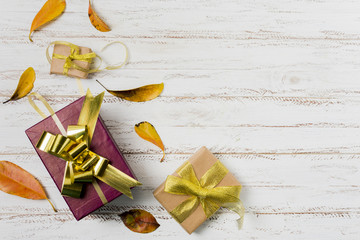 Wall Mural - Gift boxes in wrapping paper with ribbons and autumn leaves on a white wooden background