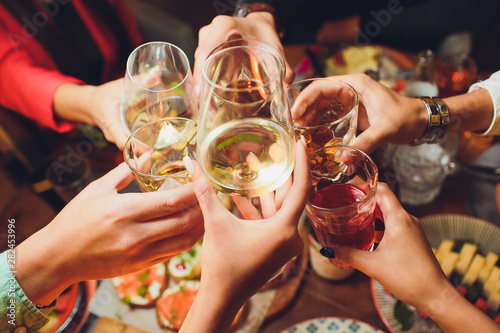 Fotografía Human hands with glasses of red wine clinking them over served table