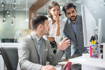 Concentrated business people looking together at computer monitor in office