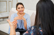 © DragonImages - Indian young businesswoman sitting on sofa and listening to her colleague with smile during business interview at office