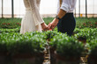 © Matan_Katz - Midsection of bride and groom holding hands in plant nursery