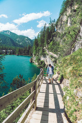 Wall Mural - man walking by hiking trail around braies lake in italy dolomites mountains