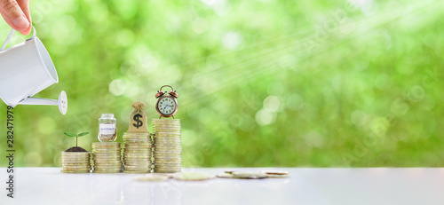 Cuadros en Lienzo Long-tern investment, time value of money concept : Clock, US dollar bag, glass jar, a small tree on steps of rising coins