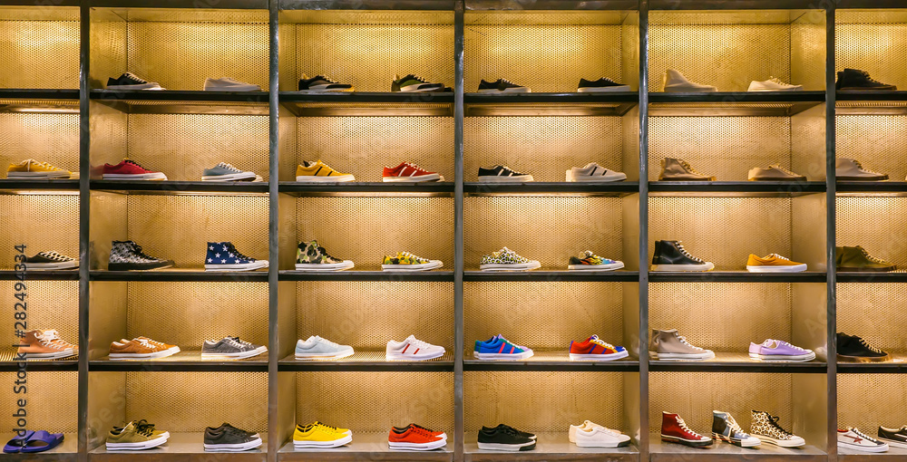 Lots of different sneakers on the showcase on market. Image of sport shoes on shop-window - obrazy, fototapety, plakaty 