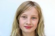 © Cat - Portrait of a young blonde smiling girl against a white background