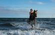 © fStop - Woman riding horse in ocean surf