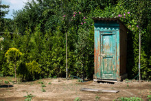 Rustic outdoor toilet stands in the garden sparkling, reflecting the sunshine light