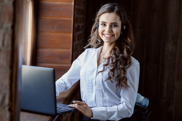 Young friendly operator woman agent with headsets working with laptop. Call Center Service. Photo of customer support or sales agent in smart casual wear.