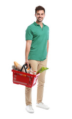 Wall Mural - Young man with shopping basket full of products isolated on white
