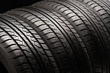  Four old used summer tires. Close-up on a black background.