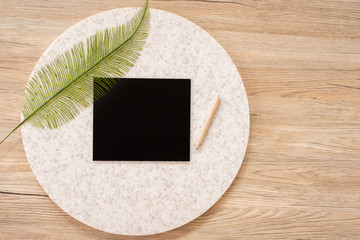 Poster - top view of blank blackboard with leaf and pencil on wooden table with copy space.eco sustainable concept.