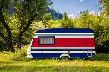 A car trailer, a motor home, painted in the national flag of Costa Rica stands parked in a mountainous. The concept of road transport, trade, export and import between countries. Travel by car