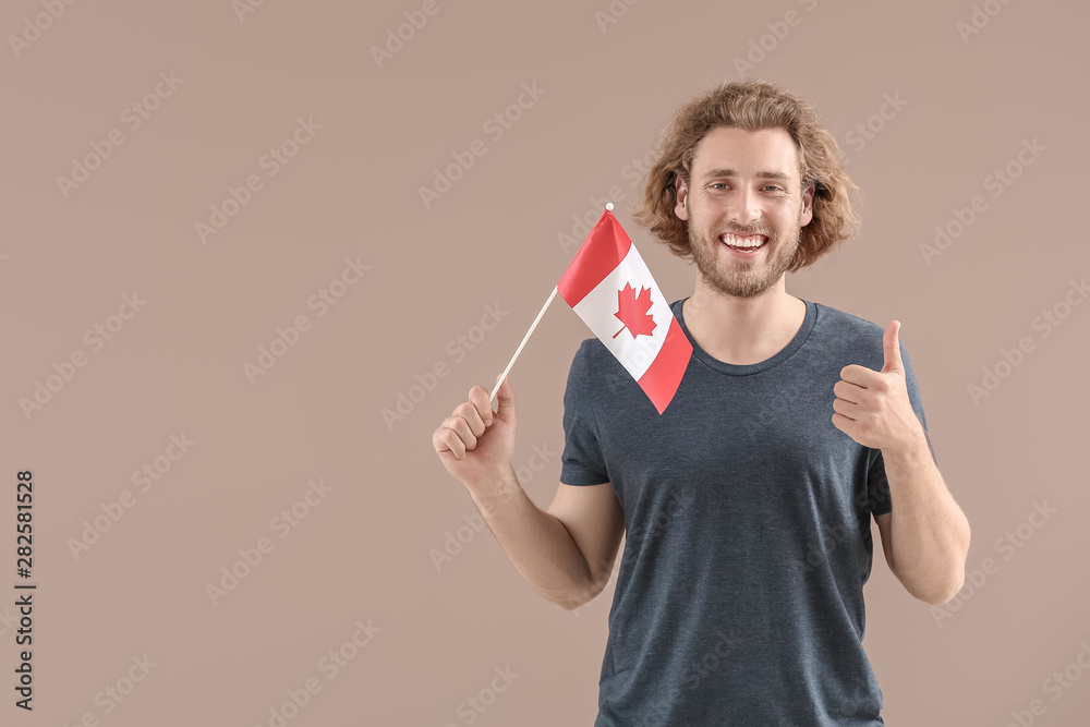 Young man with Canadian flag on color background