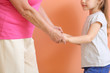 © Pixel-Shot - Cute little girl with grandmother holding hands on color background