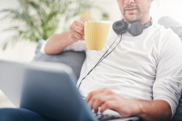 Wall Mural - Man listening to music and using laptop in the living room.