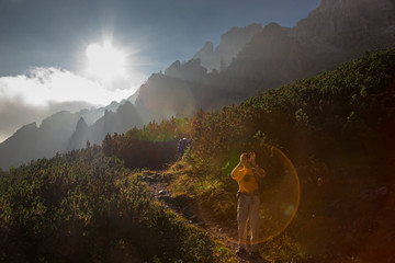 Wall Mural - a hiker takes a souvenir photo as he goes up a mountain path in the early hours of the day