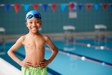 Portrait Of Boy Standing By Edge Of Swimming Pool Ready For Lesson