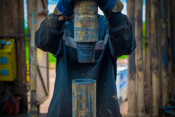 Wall Mural - Offshore oil rig worker prepare tool and equipment for perforation oil and gas well at wellhead platform. Making up a drill pipe connection. A view for drill pipe connection from between the stands