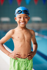 Portrait Of Boy Standing By Edge Of Swimming Pool Ready For Lesson