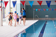 © Monkey Business - Female Coach Walks Children In Swimming Class Along Edge Of Indoor Pool