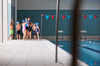 © Monkey Business - Female Coach Giving Children In Swimming Class Briefing As They Sit On Edge Of Indoor Pool