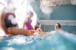 © Monkey Business - Coach In Water Gives Children Swimming Lesson As They Sit On Edge Of Pool And Splash Him