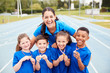 © Monkey Business - Portrait Of Children With Female Coach Showing Off Winners Medals On Sports Day
