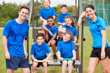 Portrait Of Children With Male And Female Coaches Preparing For Relay Race On Sports Day