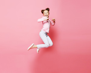 Wall Mural -  funny child girl dressed casual jumping on pink  background 