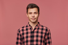Portrait Of Young Attractive Man In Checkered Shirt, Calmly Looks At The Camera, Stands Over Pink Background.