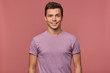 © timtimphoto - Photo of young attractive man in blanc t-shirt, cheerful looks at the camera, stands over pink background and smiles.