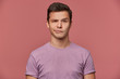© timtimphoto - Portrait of handsome frowning young man wears in blank t-shirt, looks at the camera with with a grin and doubts, stands over pink background.