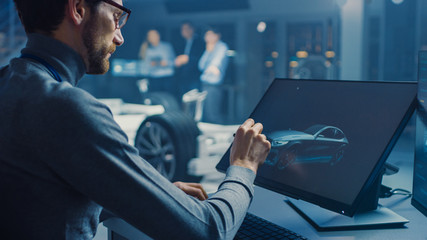 Poster - Professional Automotive Graphic Designer is Working on Concept Car Render with a Stylus Pen in a High Tech Innovative Laboratory with a Prototype Car Chassis.