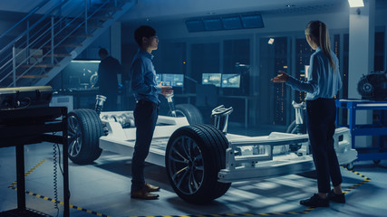 Aufkleber - Automotive Design Engineers Talking while Working on Electric Car Chassis Prototype. In Innovation Laboratory Facility Concept Vehicle Frame Includes Wheels, Suspension, Engine and Battery.